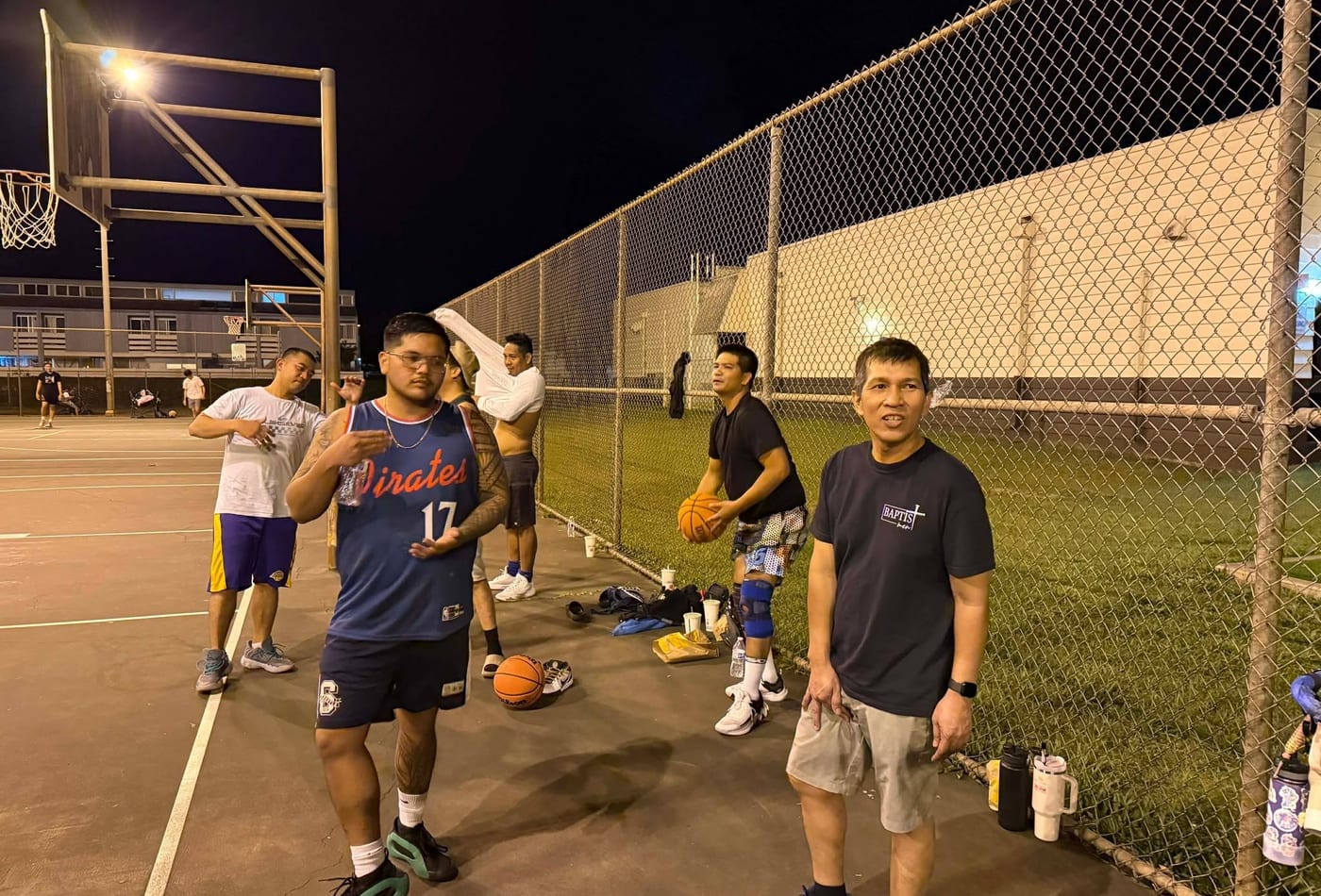 Men's fellowship group posing together on the basketball court at night