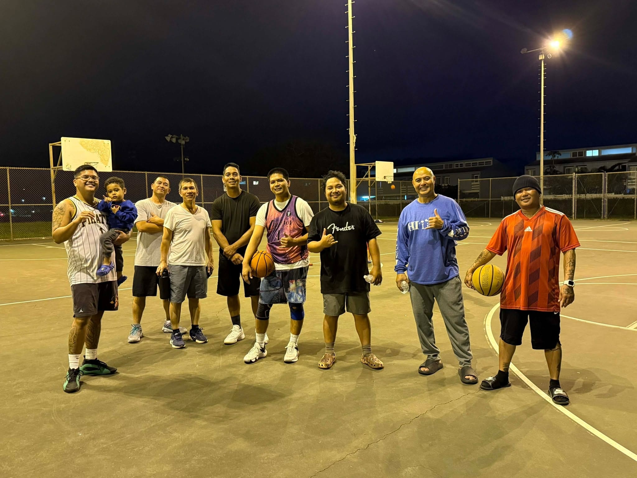 Men playing basketball together on the court at night