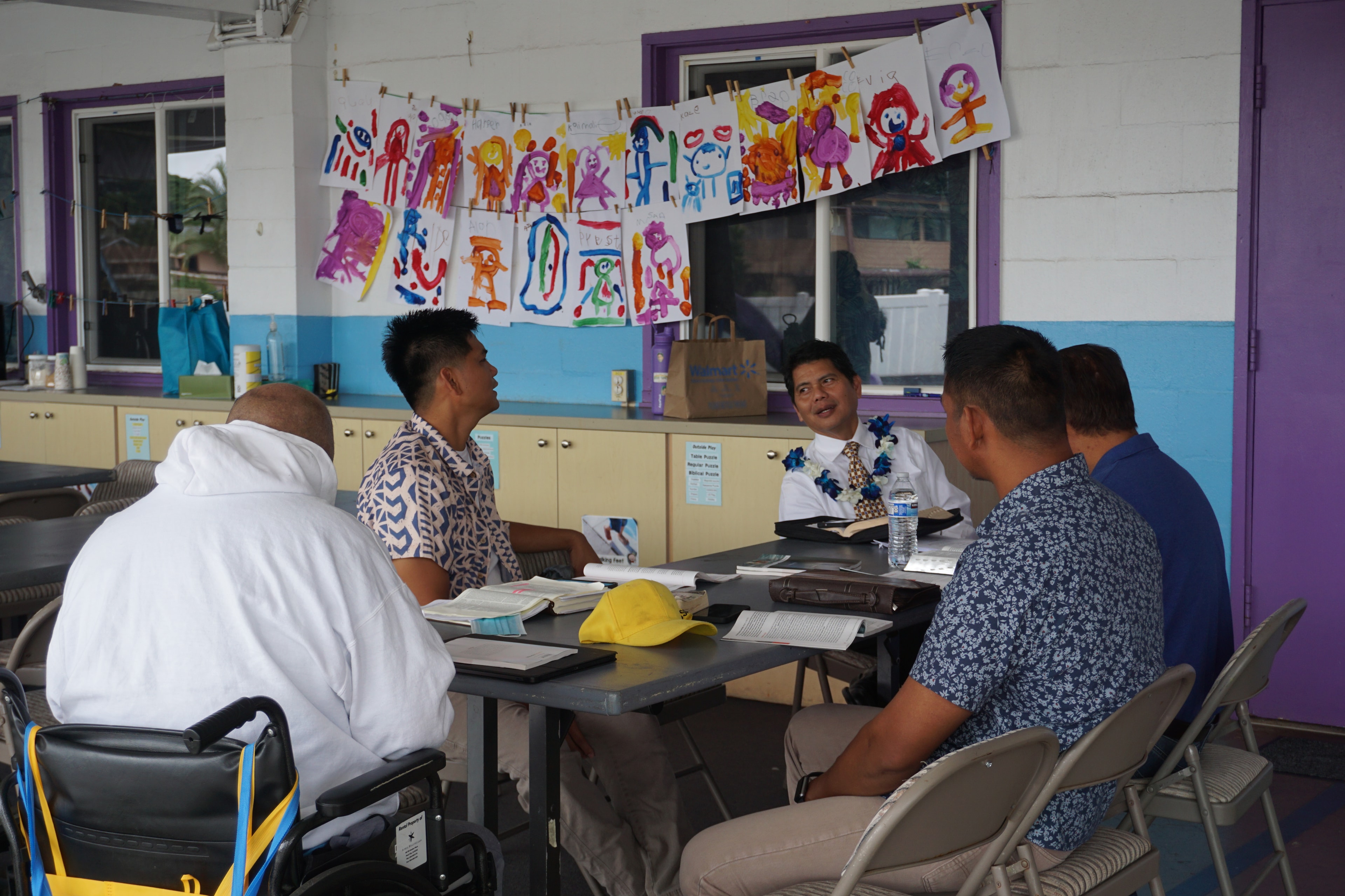 Pastor teaching Sunday School with children's artwork on the wall