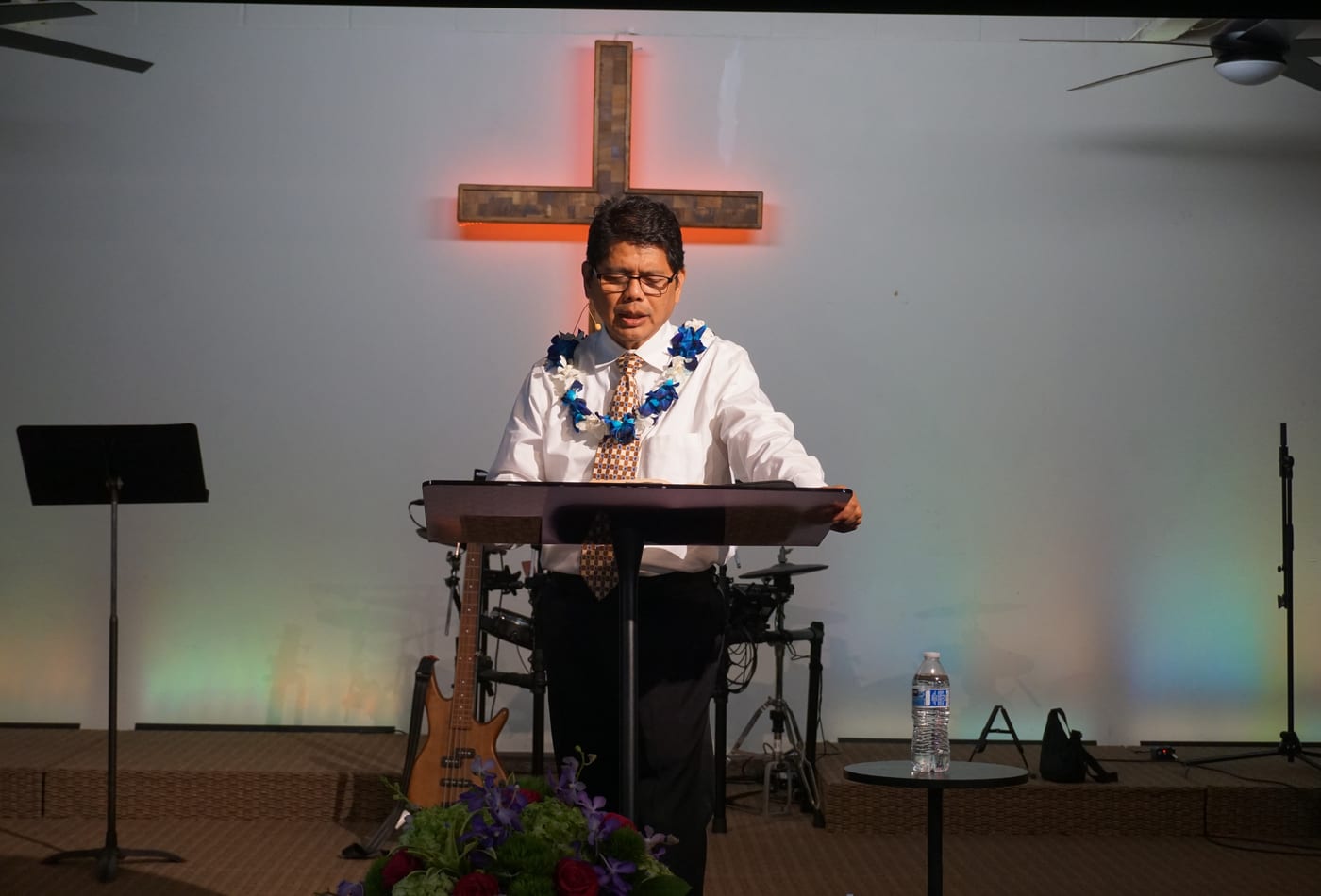 Pastor preaching at the pulpit with glowing cross backdrop