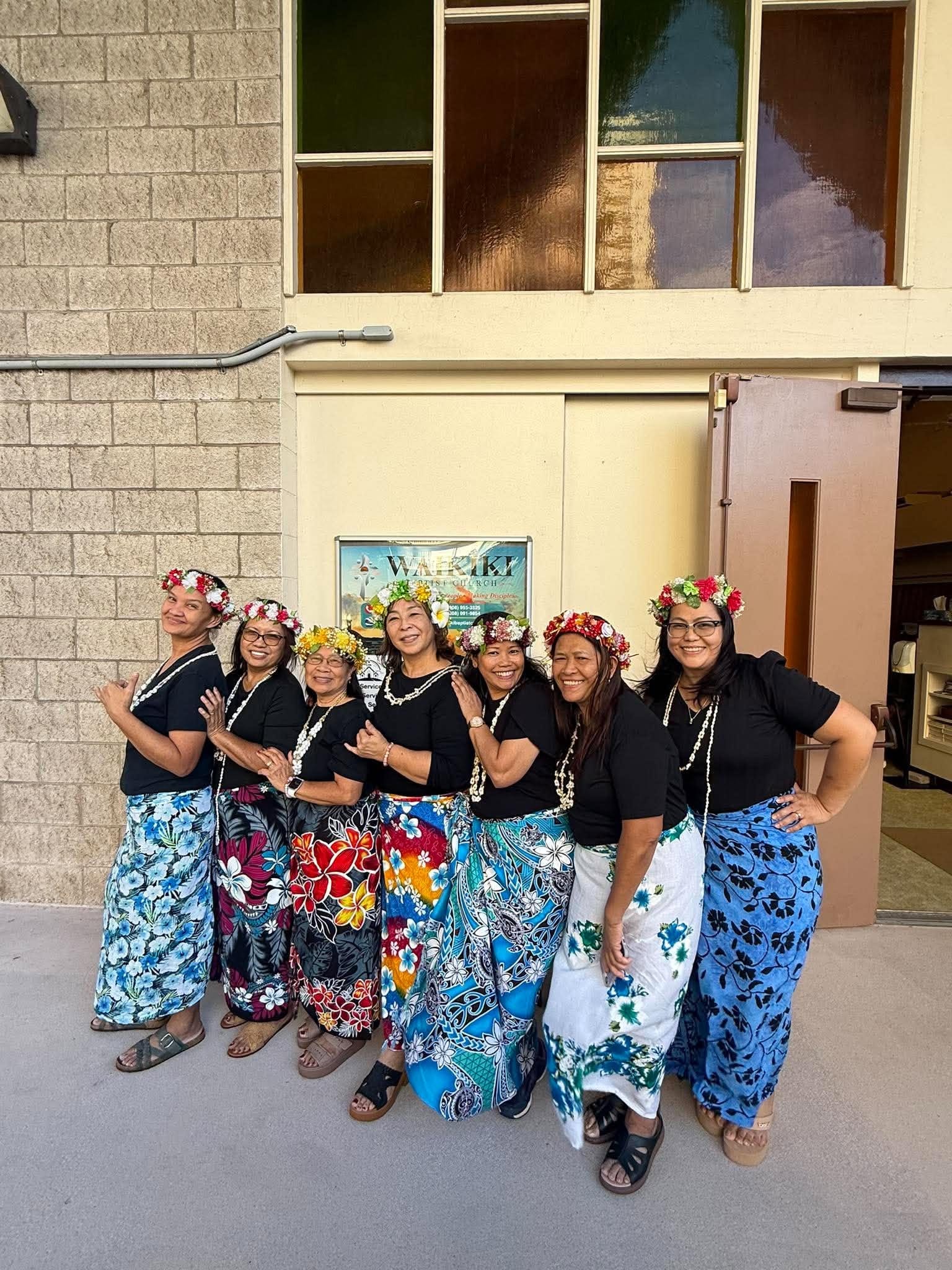 Women in colorful skirts and flower crowns gathered outside the church