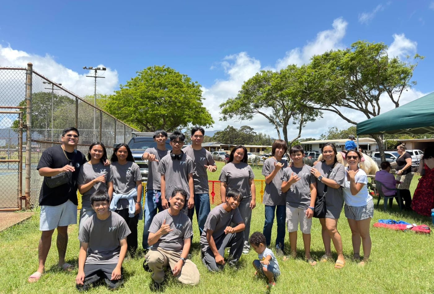 Youth group in grey YP shirts posing together outdoors on a sunny day